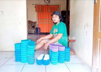 KREATIF: Zaenal Muhlisin berfoto dengan sandal jepit hasil ukirnya. (Dok. pribadi Zaenal Muhlisin/Lingkar.news)