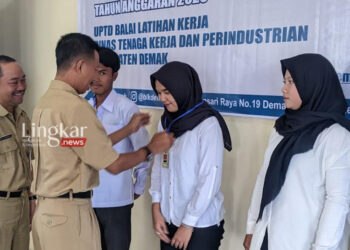 SIMBOLIS: Sekda Demak Akhmad Sugiharto didampingi Kepala Dinnakerind Demak Agus Kriyanto secara simbolis memakaikan ID Card kepada peserta PBK, Senin, 21 Agustus 2023. (M Burhanuddin Aslam/Lingkar.news)