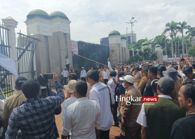 MEMANAS: Massa mengikat pagar Gedung DPR dengan tali untuk merobohkannya. (Arif Prayoga/Lingkar.news)