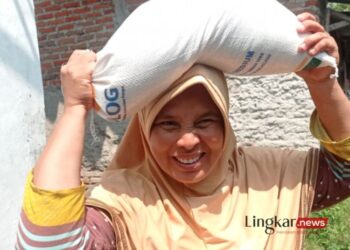 SUMRINGAH: Seorang ibu rumah tangga merasa kecapean mengangkat beras 10 kilogram di atas kepala dengan berjalan kaki dari rumah ke Kantor Kelurahan MC Rangkasbitung Timur Kabupaten Lebak. (Antara/Lingkar.news)