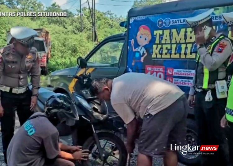 MENAMBAL BAN: Satlantas Polres Situbondo, Jawa Timur, melayani tambel ban seorang pengendara roda dua di jalur pantura Hutan Baluran. (Antara/Lingkar.news)