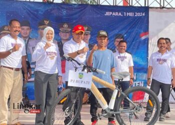 SIMBOLIS: Penjabat (Pj) Bupati Jepara, Edy Supriyanta (ketiga dari kiri) saat menyerahkan hadiah kepada salah satu warga dalam kegiatan peringatan Hari Buruh di Pantai Kartini, Rabu, 1 Mei 2024. (Muhammad Aminudin/Lingkar.news)