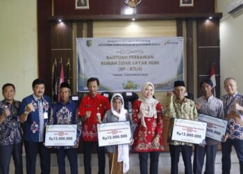 FOTO BERSAMA: Bupati Demak, Eisti’anah (keempat dari kanan) berfoto bersama warga penerima bantuan pembangunan RTLH di Balai Desa Bungo, Kecamatan Wedung, Kabupaten Demak, Rabu, 10 Juli 2024. (M. Burhanuddin Aslam/Lingkar.news)