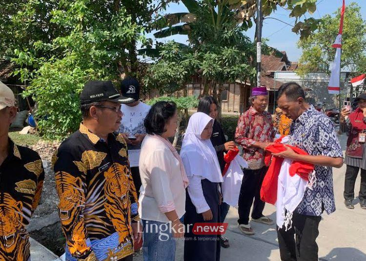 BERBAGI: Sekda Demak, Akhmad Sugiharto bersama pejabat Pemkab Demak membagikan bendera merah putih kepada warga Desa Kuwu, Kecamatan Dempet, pada Selasa, 6 Agustus 2024. (M. Burhanuddin Aslam/Lingkar.news)