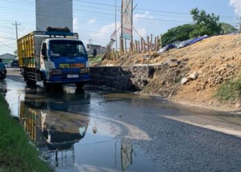 MELINTAS: Tampak sebuah truk melintas di jalan yang basah akibat rembesan air dari titik bekas jebol tanggul Sungai Jratun, Kecamatan Karanganyar, Kabupaten Demak pada Minggu, 4 Agustus 2024. (M. Burhanuddin Aslam/Lingkar.news)