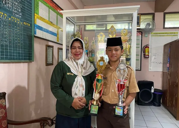 RAIH PRESTASI: Kepala SD Krandon Tri Kurniawati mendampingi Muh Arwani Hafidz siswa kelas 5 yang mendapat Juara 1 kategori wudhu dan sholat pada Lomba MAPSI Tingkat Kabupaten Kudus tahun 2024. (Nisa Hafizhotus Syarifa/Lingkar.news)