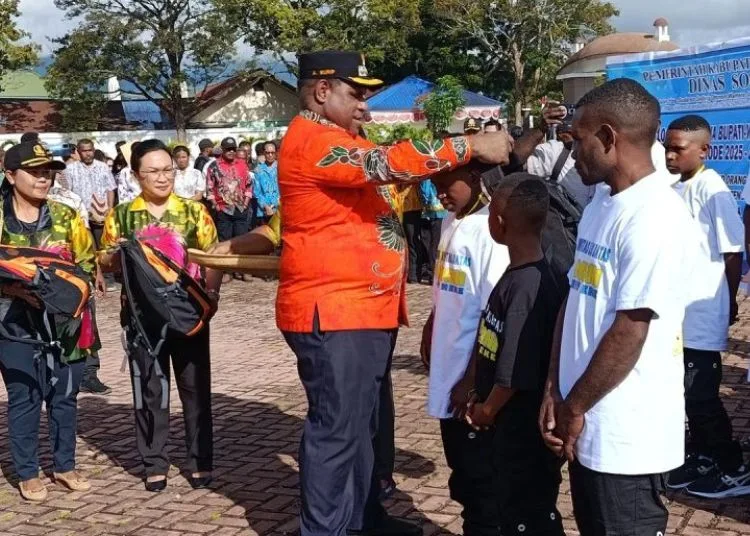 SIMBOLIS: Bupati Jayawijaya Atenius Murib ketika menyematkan tanda peserta dan pemberian tas sebagai simbol pelepasan 50 anak jalanan untuk menempuh pendidikan di Yogyakarta. (Antara/Lingkar.news)