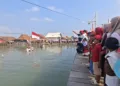 Warga Timbulsloko melakukan upacara Detik-Detik Proklamasi HUT ke-81 RI di wilayah yang kini tergenang rob, Senin (17/8/2026). (M. Burhan A – Lingkar.news)