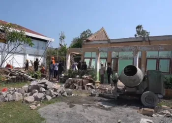 Suasana di lokasi proyek revitalisasi SDN 01 Margorejo, Kecamatan Dawe, Kabupaten Kudus. Tampak beberapa pekerja dan sejumlah orang sedang meninjau area di sekitar bangunan sekolah yang sedang dalam proses perbaikan.