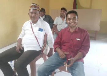 Maksimus Ponggu berkemeja putih dan Yosef Bagung berkemeja merah sedang duduk santai di sela-sela rehat perhitungan suara Pemilihan Kepala Desa Lenda 2026.
